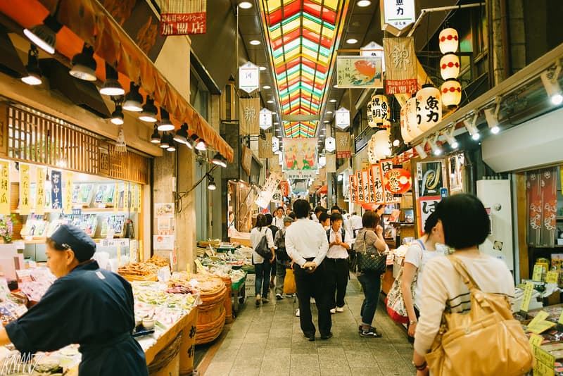 Khách hàng đi dạo dọc lối đi đầy màu sắc ở Chợ Nishiki, Kyoto, ngắm nhìn các quầy thức ăn
